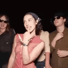 a group of people are standing next to each other in a dark room and a woman is making a funny face .
