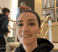 a woman is smiling in front of a green arrow pointing to the right