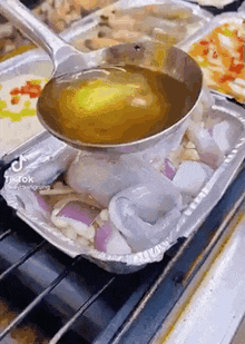 a ladle is being used to pour liquid over a tray of food on a grill .