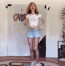 a woman dancing in front of a sign that says over
