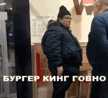 a man in a black jacket is standing next to another man in a black hat and glasses ..