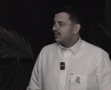 a man wearing glasses and a white shirt has a dji logo on his pocket