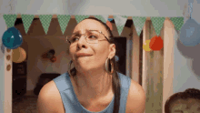 a woman wearing glasses and hoop earrings making a face