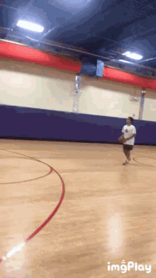 a basketball player dribbles the ball on a court with a purple wall behind him