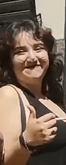 a woman is making a funny face and smiling while holding her chest .