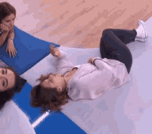 a woman is laying on her stomach on the floor while another woman looks on