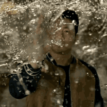 a man is standing in front of a wall of water splashing on his face .