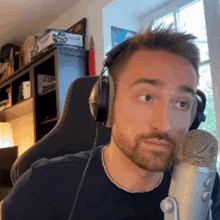 a man wearing headphones is sitting in front of a microphone and making a funny face .