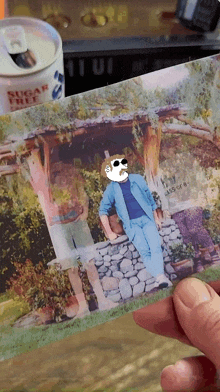 a person is holding a picture of a man in front of a can that says sugar free on it