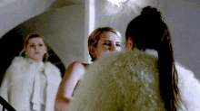 a woman in a fur coat is standing next to another woman .