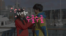a boy and a girl are standing next to each other in front of a harbor