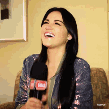 a woman is laughing while holding a microphone with the word gamar on it