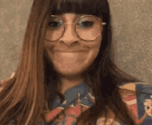 a woman wearing glasses and a colorful shirt is smiling .