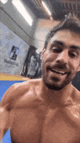 a man without a shirt is smiling in front of a wall that has the letter f.