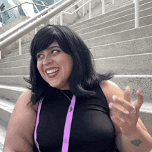 a woman wearing a black top and a purple lanyard with a j on it smiles