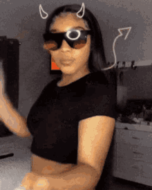 a woman wearing sunglasses and a black crop top is dancing .