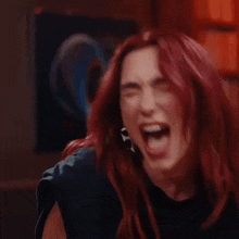 a woman with red hair and hoop earrings is smiling and looking at the camera .