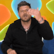 a man in a black jacket is making a gesture