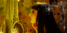 a woman is looking at herself in a mirror in front of a floral wallpaper