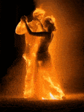a silhouette of a man and woman dancing with flames surrounding them
