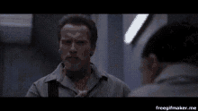 a man is talking to another man in a room with a window in the background .