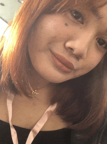 a close up of a woman 's face with a pink lanyard