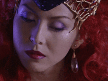 a close up of a woman 's face with red hair and a crown on her head