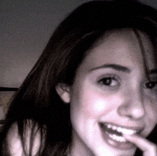 a close up of a woman 's face with a finger in her mouth .