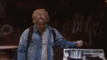 a man in a denim jacket is stirring a pot on a stove with a spoon