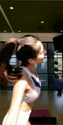 a woman in a sports bra and white shorts is standing on a yoga mat in a gym