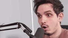 a man is sitting in front of a microphone and making a surprised face
