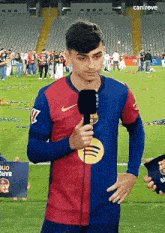 a man holding a microphone on a soccer field with the word canireve on the bottom right