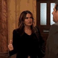 a woman in a black jacket is talking to a man in a suit in a courtroom .