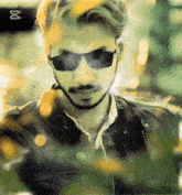 a man wearing sunglasses and a leather jacket with the letter m on the bottom left