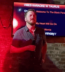 a man stands in front of a screen that says vibes karaoke w taurus on it