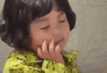 a little girl is covering her face with her hand .