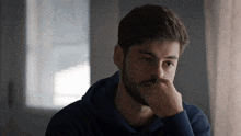 a man with a beard is sitting in front of a window