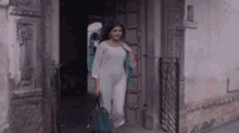 a woman in a white dress is walking out of a doorway