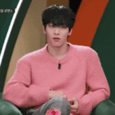a man in a pink sweater is sitting on a chair