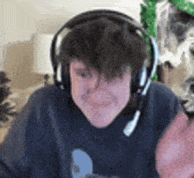 a young man wearing headphones and a microphone is sitting in front of a computer .
