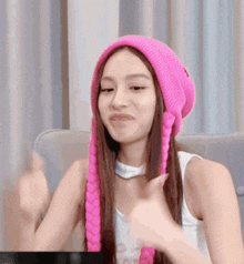 a woman wearing a pink hat and braided hair is giving a thumbs up