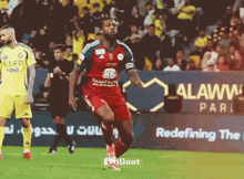 a soccer player wearing a red and green jersey that says kafd
