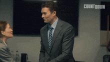 a man in a suit shakes hands with a woman in front of a sign that says " countdown "