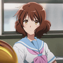 a girl in a school uniform with a pink bow looks at the camera