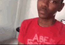a man wearing a red t-shirt with the word abercrombie on it is making a funny face .