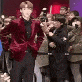 a man in a red velvet suit is standing in front of a crowd of people .