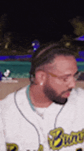 a man with a beard and glasses is wearing a baseball uniform .