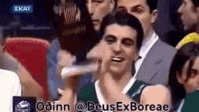 a man in a basketball uniform is giving a thumbs up in a crowd of people .