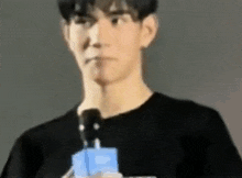 a man in a black shirt is holding a microphone in his hand .