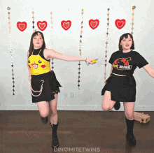 two women are dancing in front of a wall with hearts and stars and the words dinomitetwins on the bottom